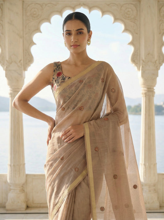 Woman in a beige saree with floral patterns standing in front of an architectural structure with a scenic background. Light Grey Jamdani Cotton Woven Saree for women