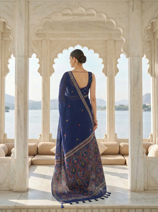 Woman in a blue saree standing in front of an archway with a scenic view. Navy Blue Patola Jamdani Cotton Saree for women