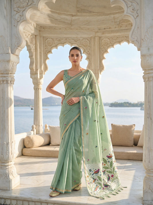 Woman in a light green saree with floral patterns standing in front of an architectural structure with a scenic background. Pista Green Jamdani Cotton Saree